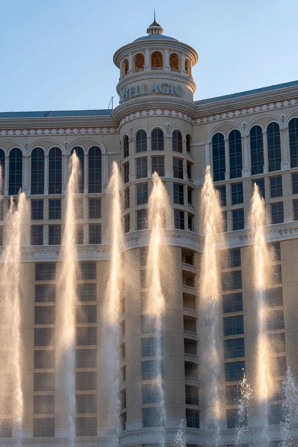The Bellagio fountains firing in front of the hotel facade in low evening light