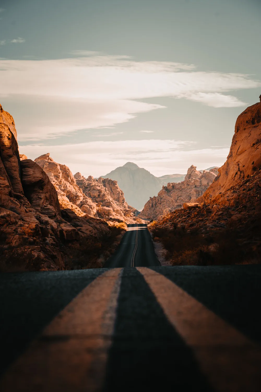An empty road running between red sandstone walls in the Valley of Fire at sunset