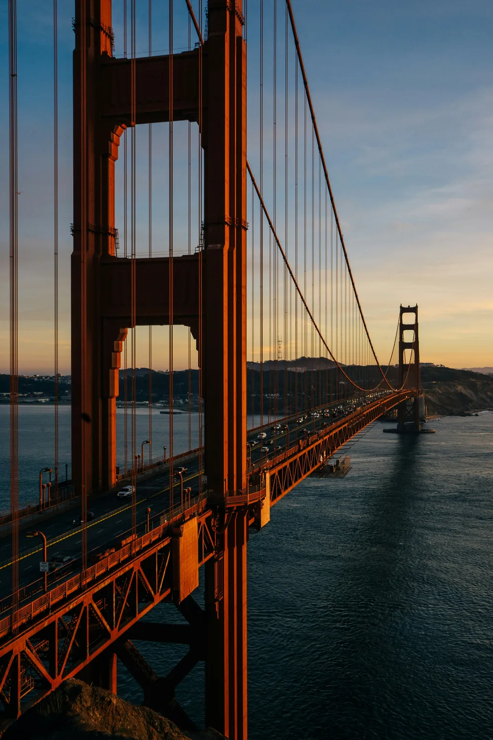 The Golden Gate Bridge tower and span in low evening sun above the bay