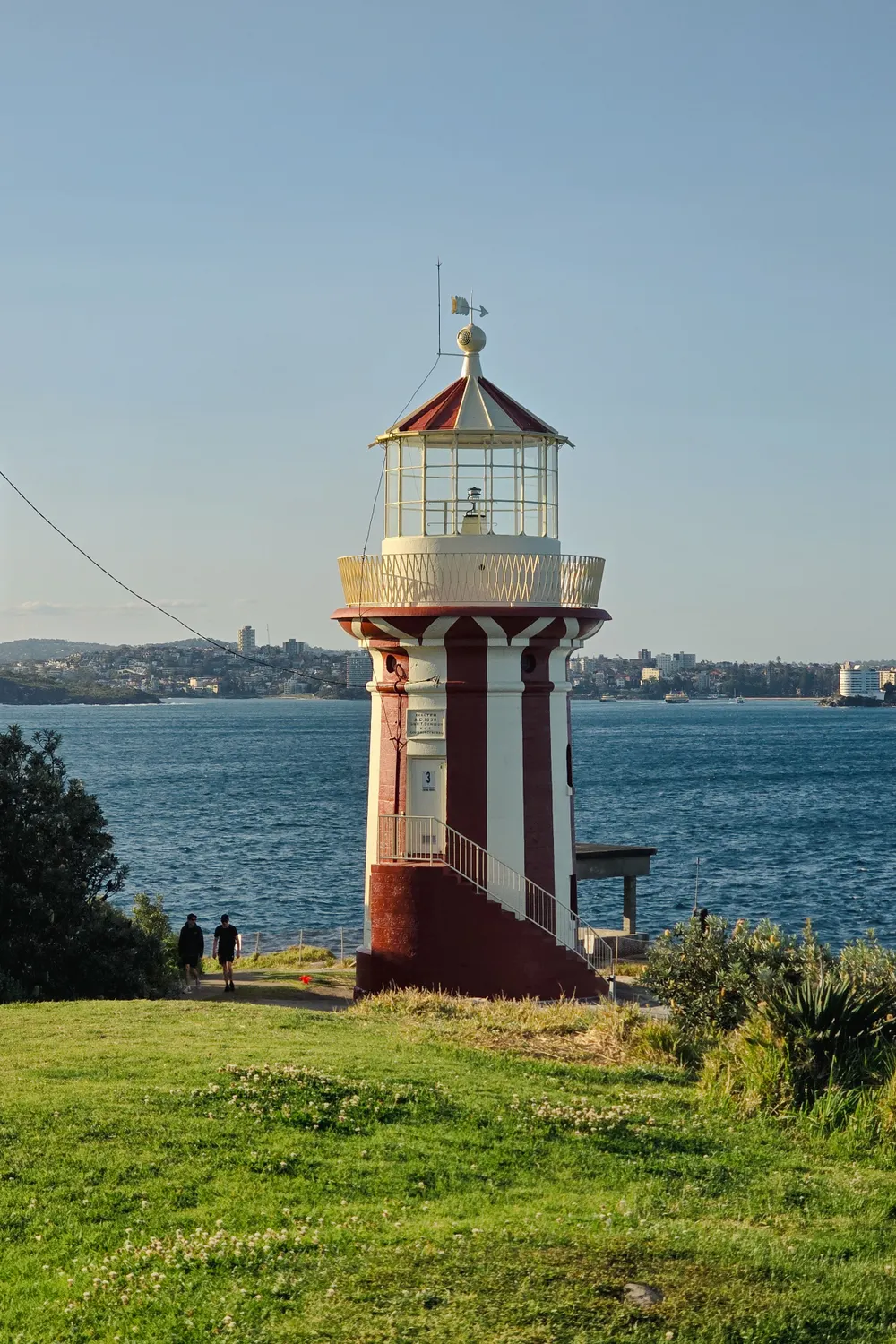 Hornby Lighthouse at South Head in late-afternoon light, with the harbour and Sydney in the distance behind it