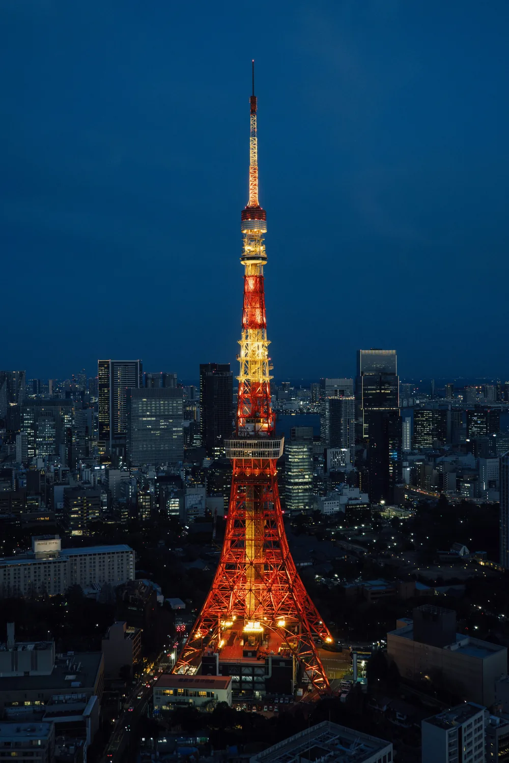 Tokyo Tower lit orange and white at night above the surrounding city lights