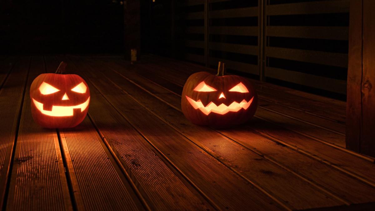 Two carved jack-o'-lanterns glowing on a dark wooden porch