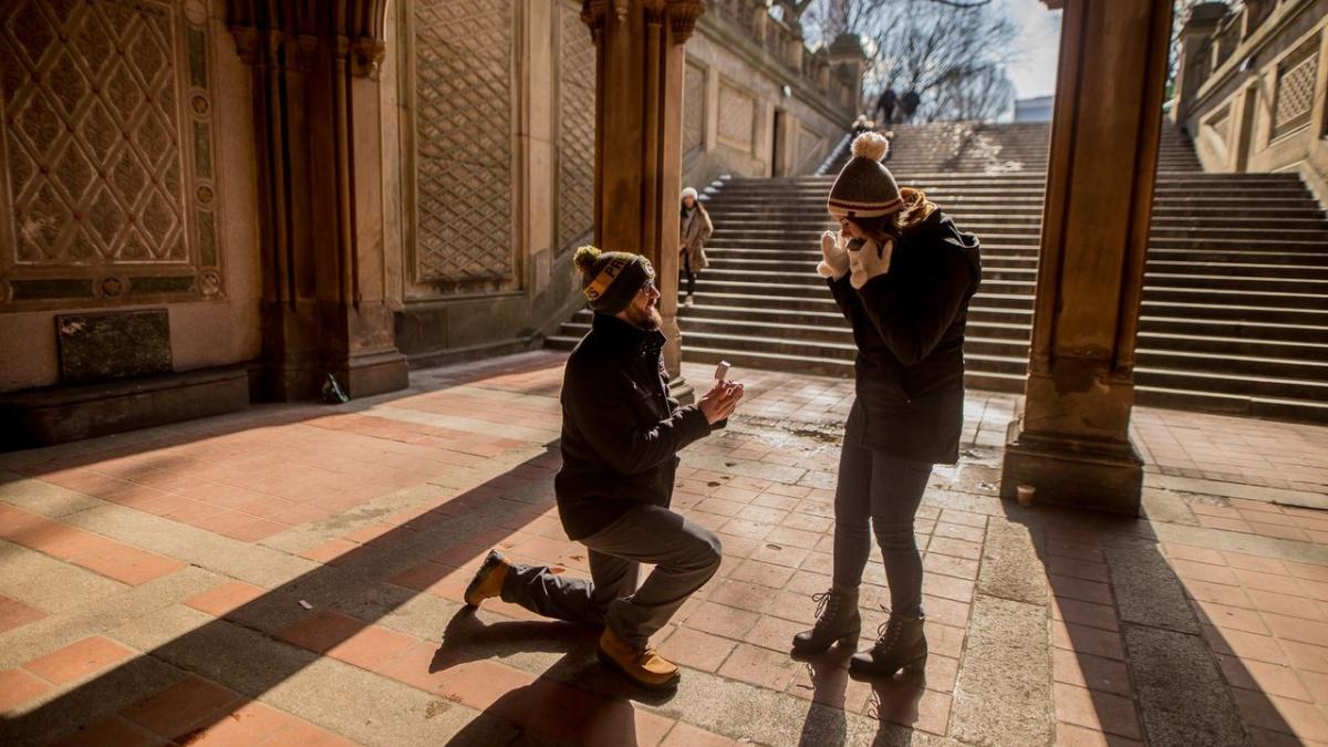 A man on one knee proposes under the arches of Bethesda Terrace in Central Park