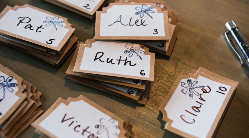 Handwritten wedding place cards with guests' names and table numbers
