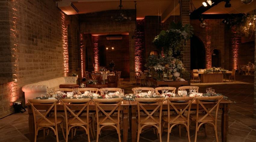 Long reception tables laid for dinner in a softly lit brick venue