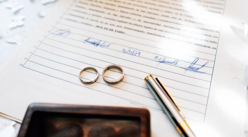 Two wedding bands and a pen on a signed marriage certificate