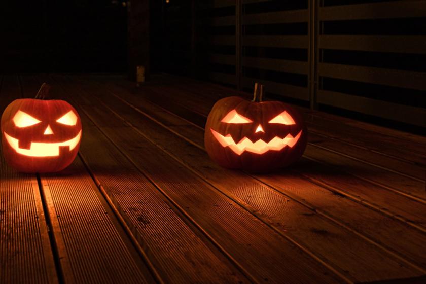 Two carved jack-o'-lanterns glowing on a dark wooden porch