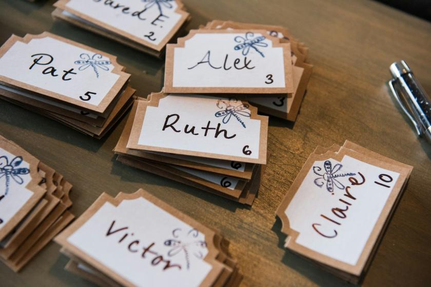 Handwritten wedding place cards with guests' names and table numbers