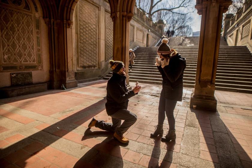 A man on one knee proposes under the arches of Bethesda Terrace in Central Park