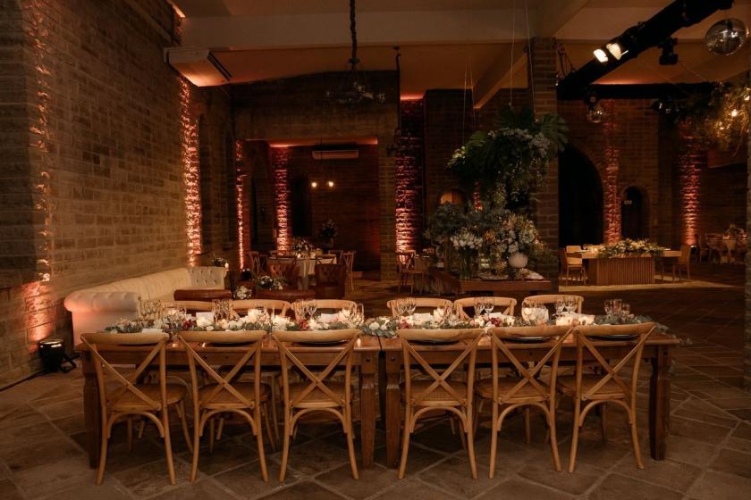 Long reception tables laid for dinner in a softly lit brick venue