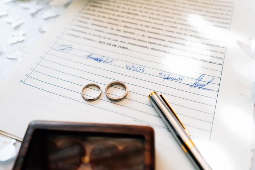 Two wedding bands and a pen on a signed marriage certificate
