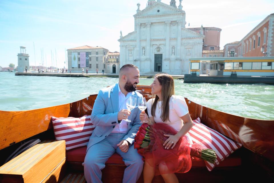 Newly engaged couple celebrating their marriage proposal on a romantic boat ride in Venice, Italy