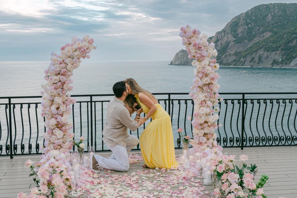 Surprise marriage proposal at a romantic floral setup overlooking the sea in Cinque Terre, Italy