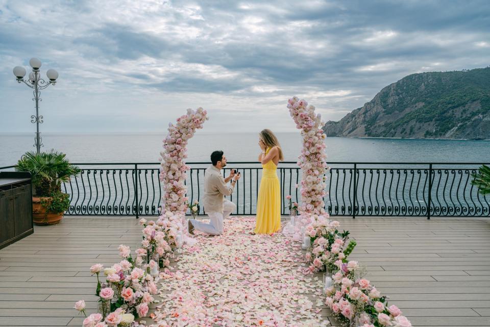 Romantic marriage proposal setup with pink flowers overlooking the sea in Cinque Terre, Italy