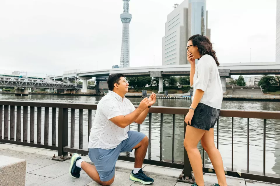 A proposal on a riverside walk in Tokyo, with the Tokyo Skytree behind the couple