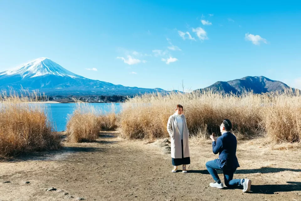 A proposal on a path through tall grasses with snow-capped Mount Fuji behind