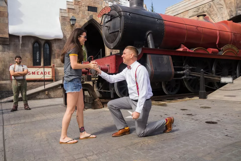 A proposal beside the red Hogwarts Express locomotive at the Wizarding World of Harry Potter in Orlando
