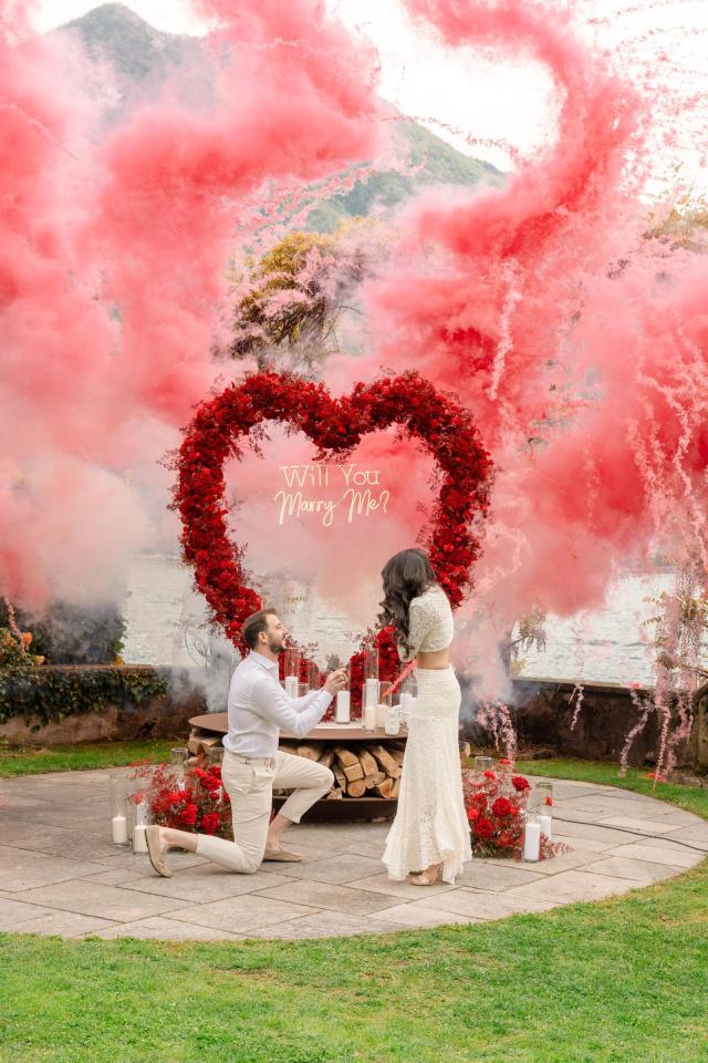 Surprise marriage proposal with pink floral decorations and romantic smoke effects in Italy