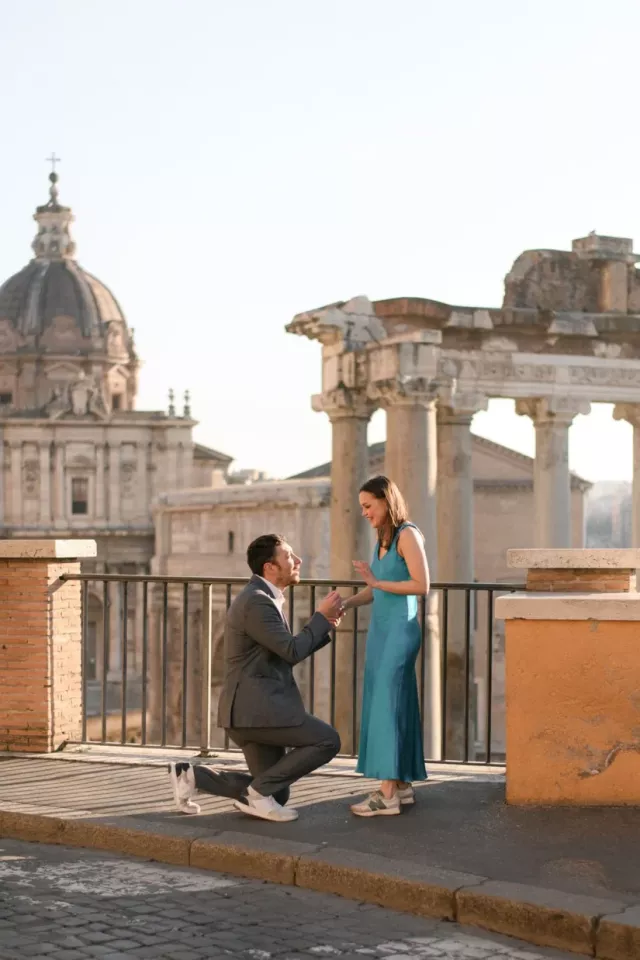 A sunrise proposal above the Roman Forum, he is on one knee with the ruins and a church dome behind