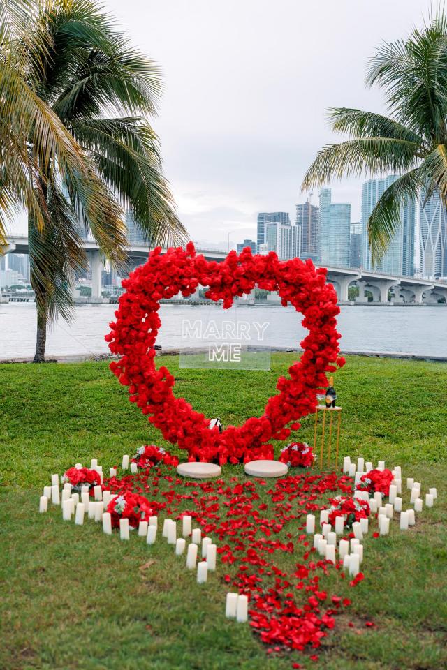 Red heart-shaped rose arch proposal setup in a Miami waterfront park