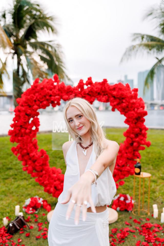 Woman posing beneath a red floral heart arch in Miami