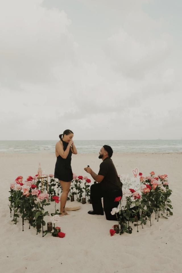 Couple surrounded by red and white rose proposal décor on Miami Beach