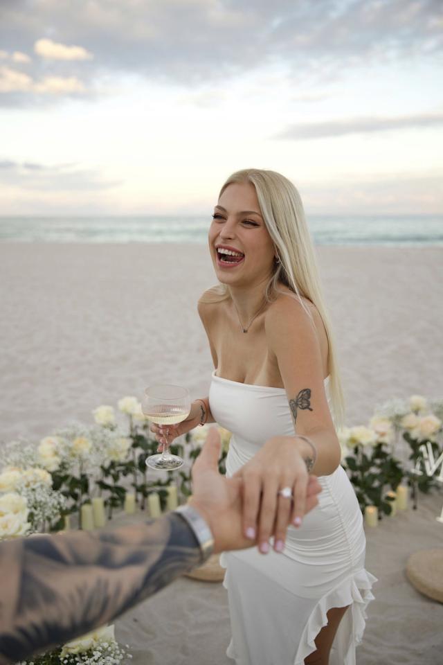 Woman smiling beside white floral proposal décor on Miami Beach
