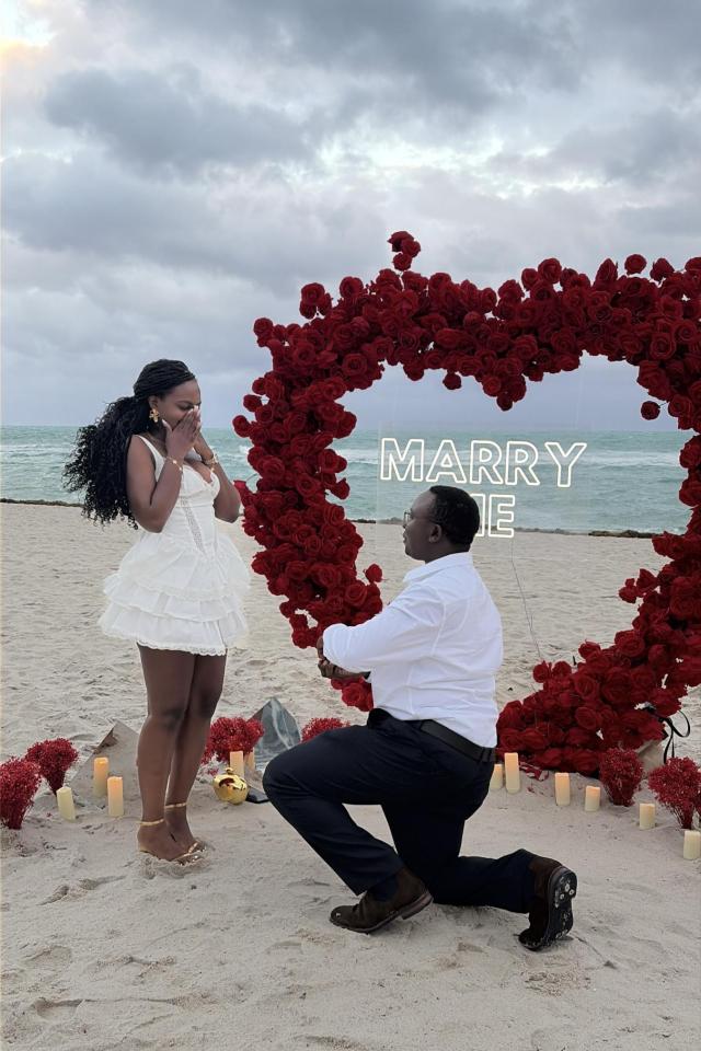 Man proposing beneath a red heart-shaped rose arch on Miami Beach