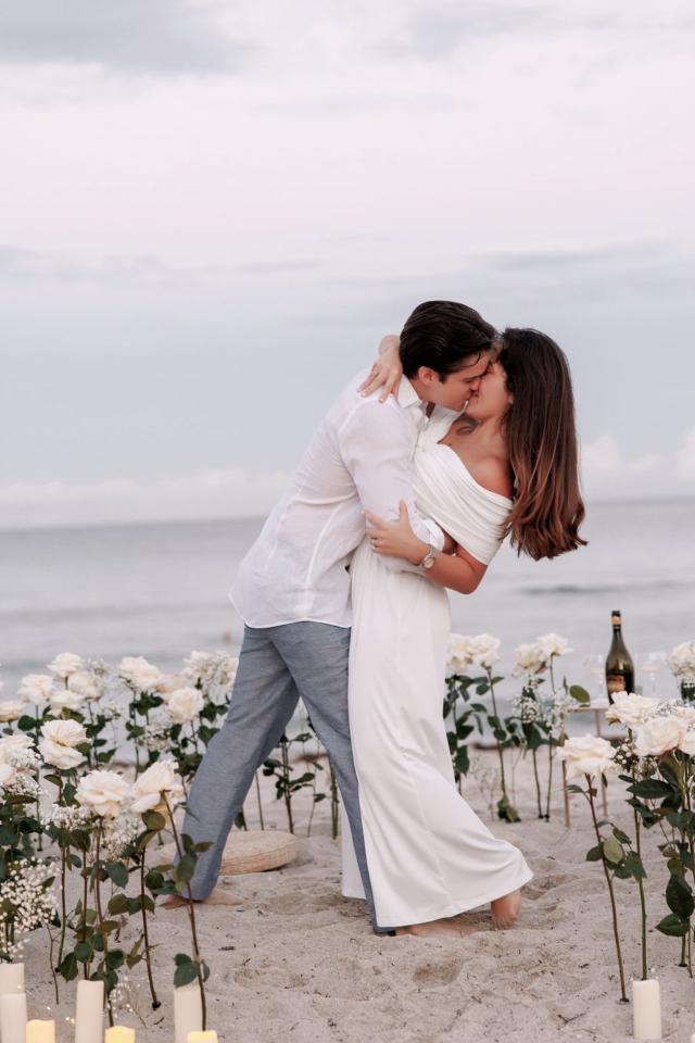 Couple kissing inside a white floral proposal setup on Miami Beach