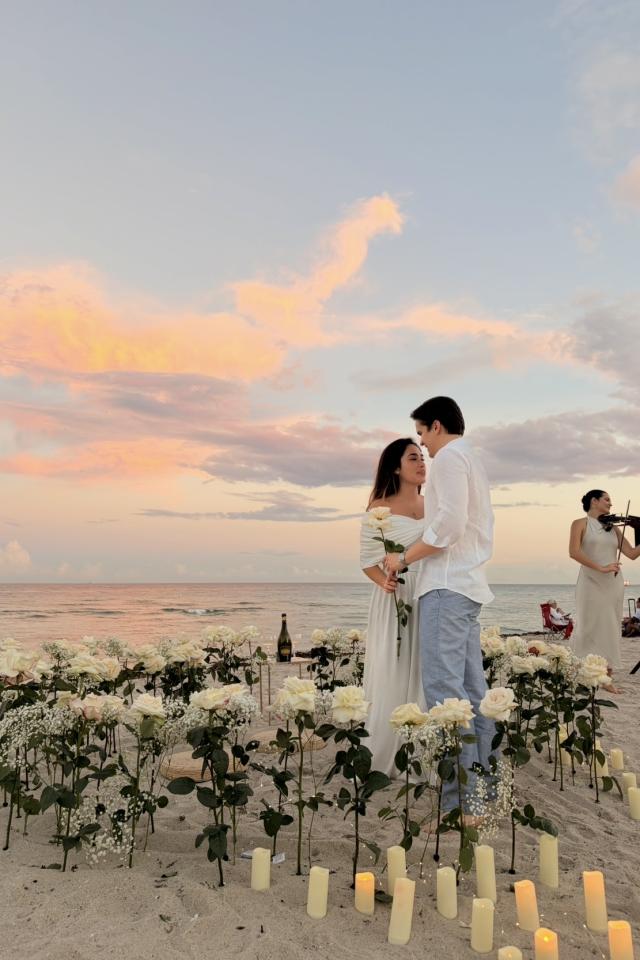 Romantic candlelit beach proposal with fresh flowers at sunset