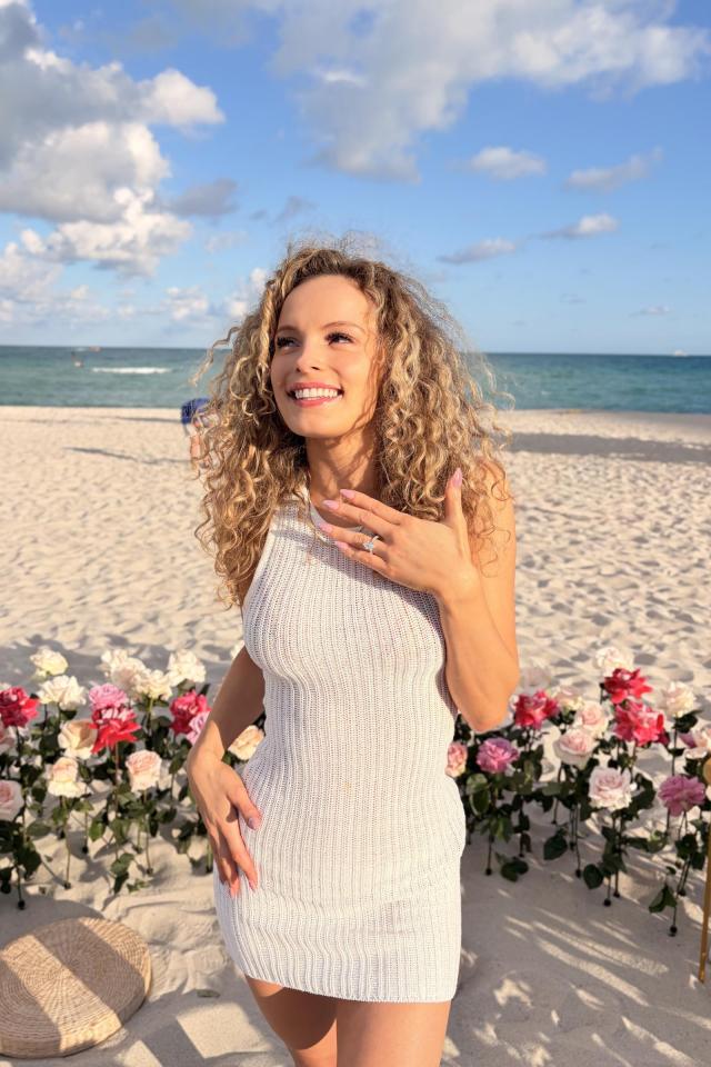 Woman celebrating beside pink and white beach proposal flowers