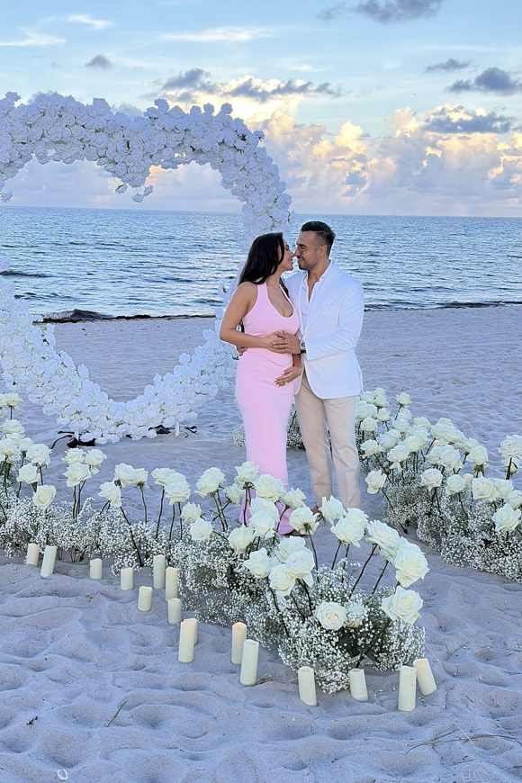 Couple embracing inside an elegant white floral heart arch