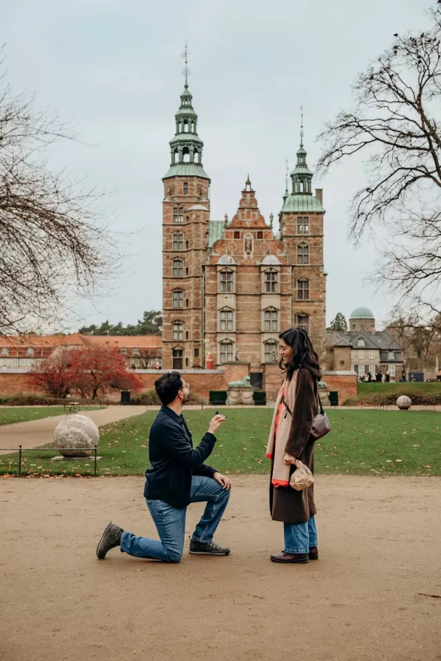A proposal on the gravel in front of Rosenborg Castle in Copenhagen, the castle's brick towers and green copper spires behind them