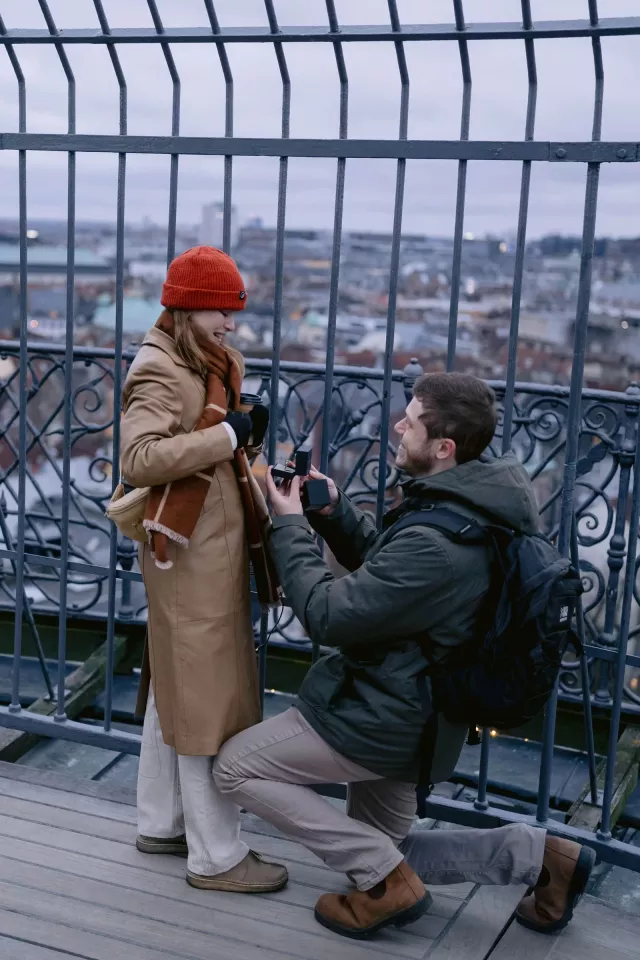 A winter proposal on the wrought-iron viewing platform of the Round Tower, with the rooftops of Copenhagen below